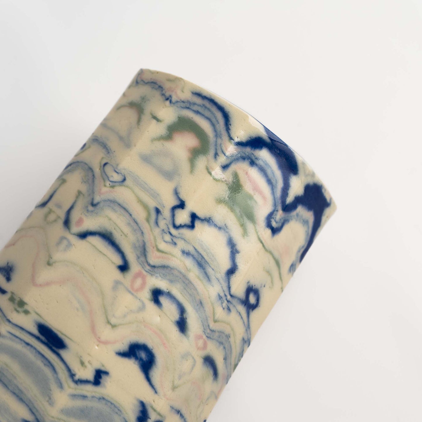 Vintage cylindrical Nerikomi marbled ceramic vase with swirling blue, green, and pink tones on an off-white ground, signed and dated 1982.