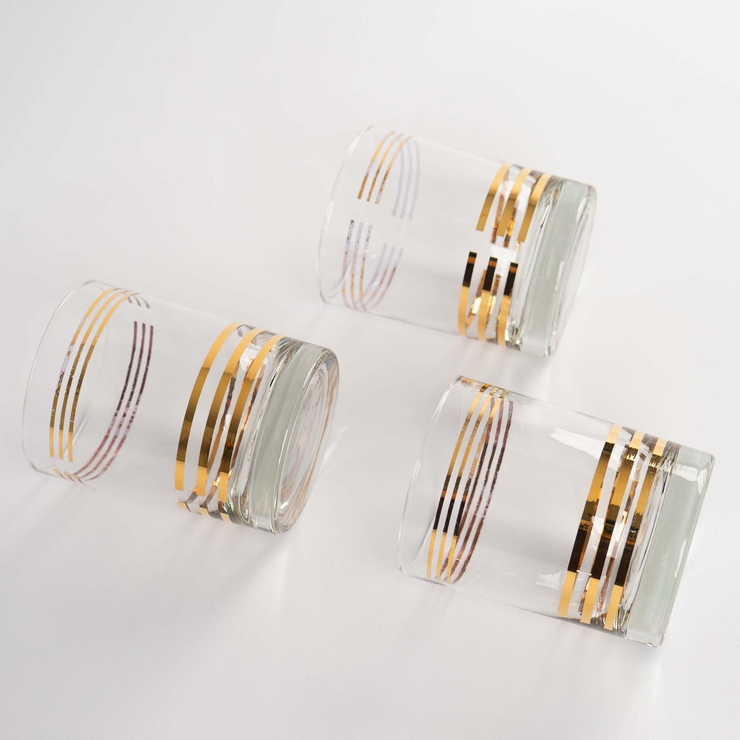 Set of three mid century lowball cocktail glasses with horizontal gold stripes 