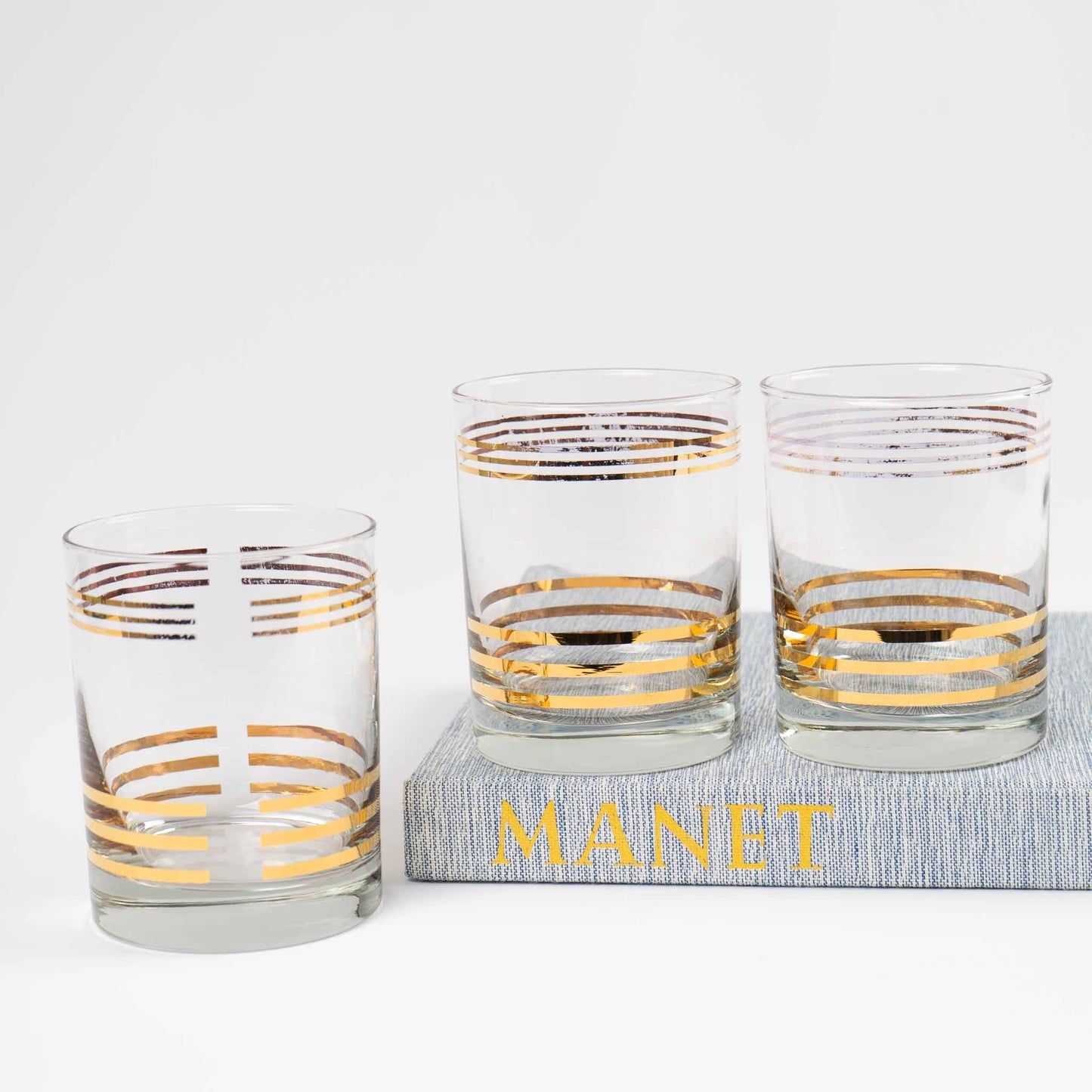 Set of three vintage lowball cocktail glasses with horizontal gold stripes 