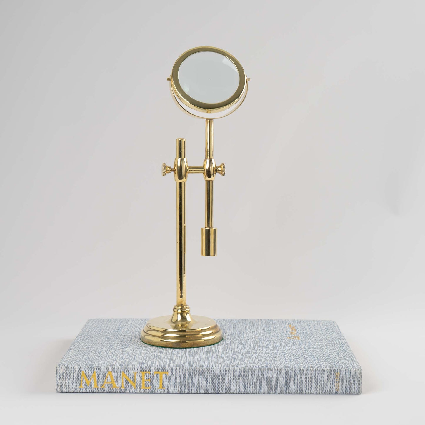 Vintage brass magnifying glass with adjustable stand by Sarreid, featuring brass finish and clear magnifying lens, marked Made in Korea