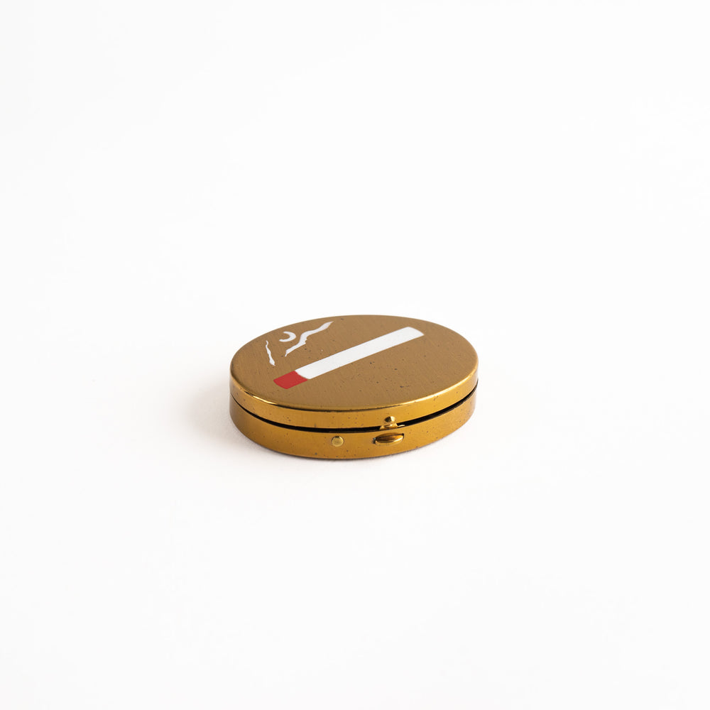 
                  
                    vintage oval brass pocket ashtray with painted cigarette design
                  
                