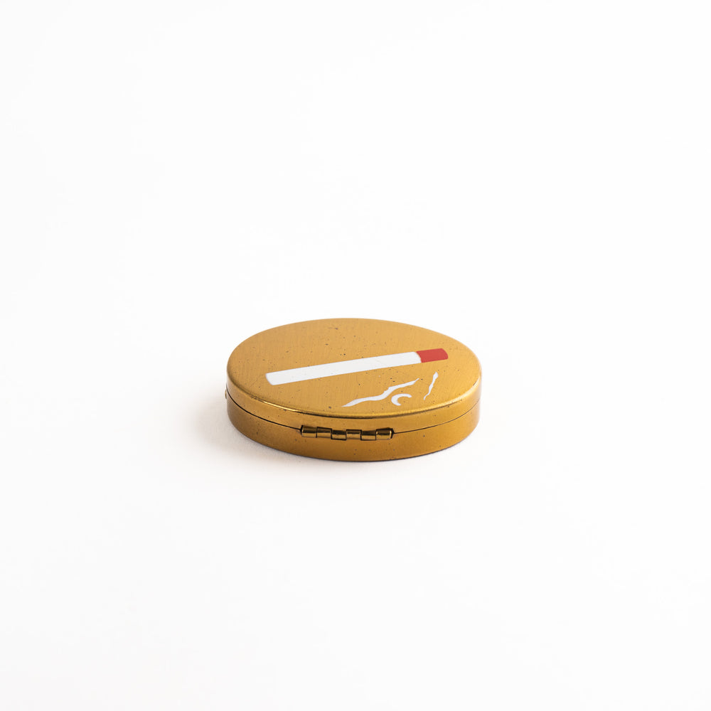 
                  
                    vintage oval brass pocket ashtray with painted cigarette design
                  
                