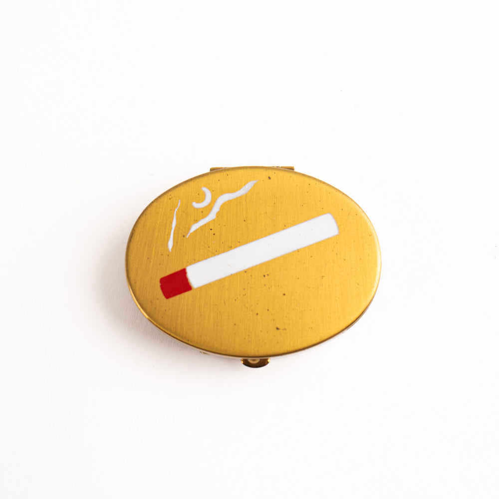 
                  
                    vintage oval brass pocket ashtray with painted cigarette design
                  
                