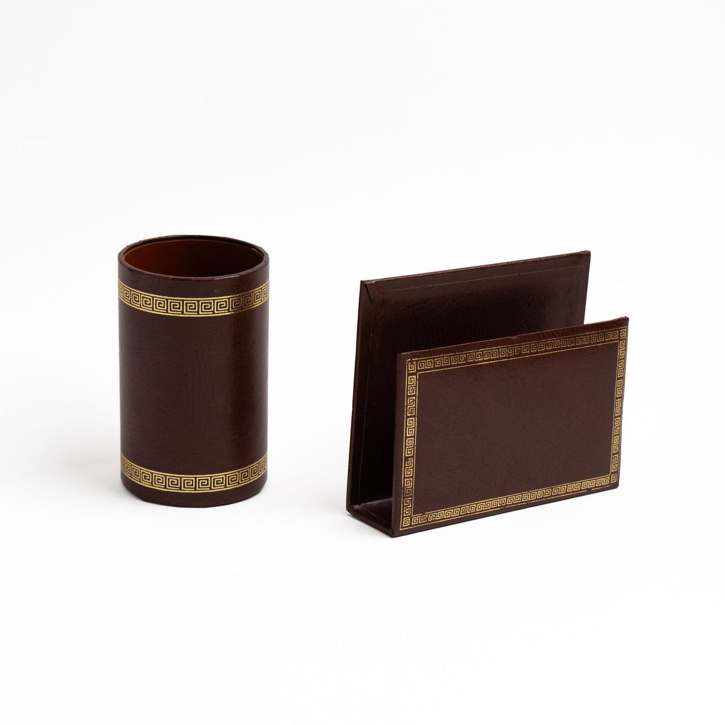 Close-up of brown leather pen/pencil holder cup and letter holder with embossed gold Greek key border detail.