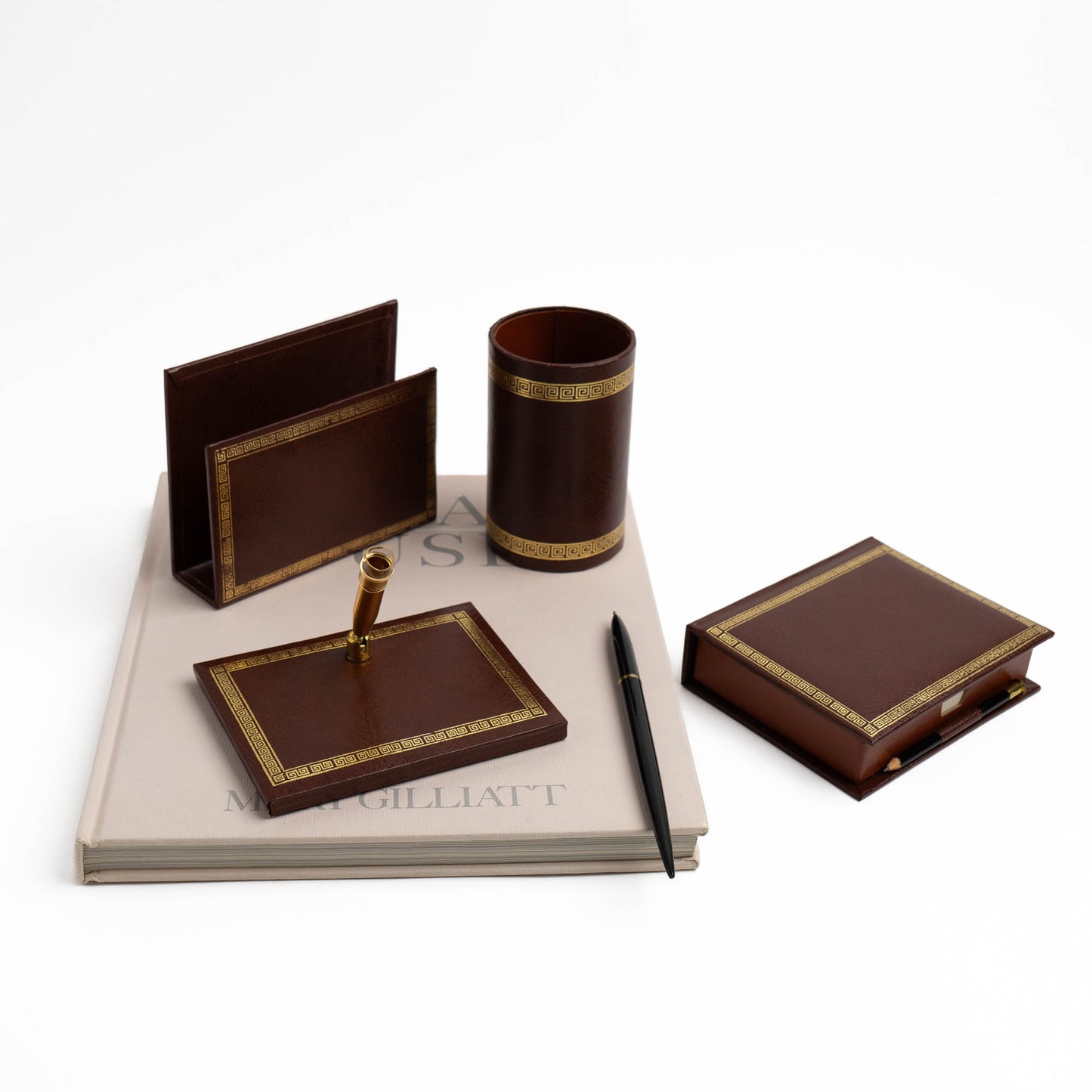 Vintage brown leather desk organizer set with gold Greek key trim, showing all four pieces arranged together on a vintage book
