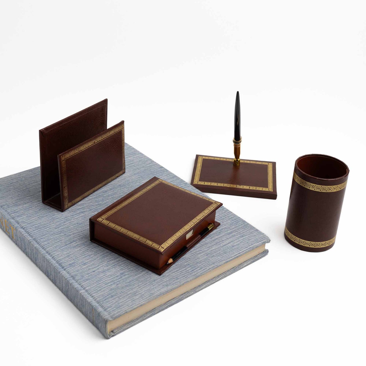 Vintage brown leather desk set with gold Greek key trim, showing all four pieces arranged together on top of a vintage book