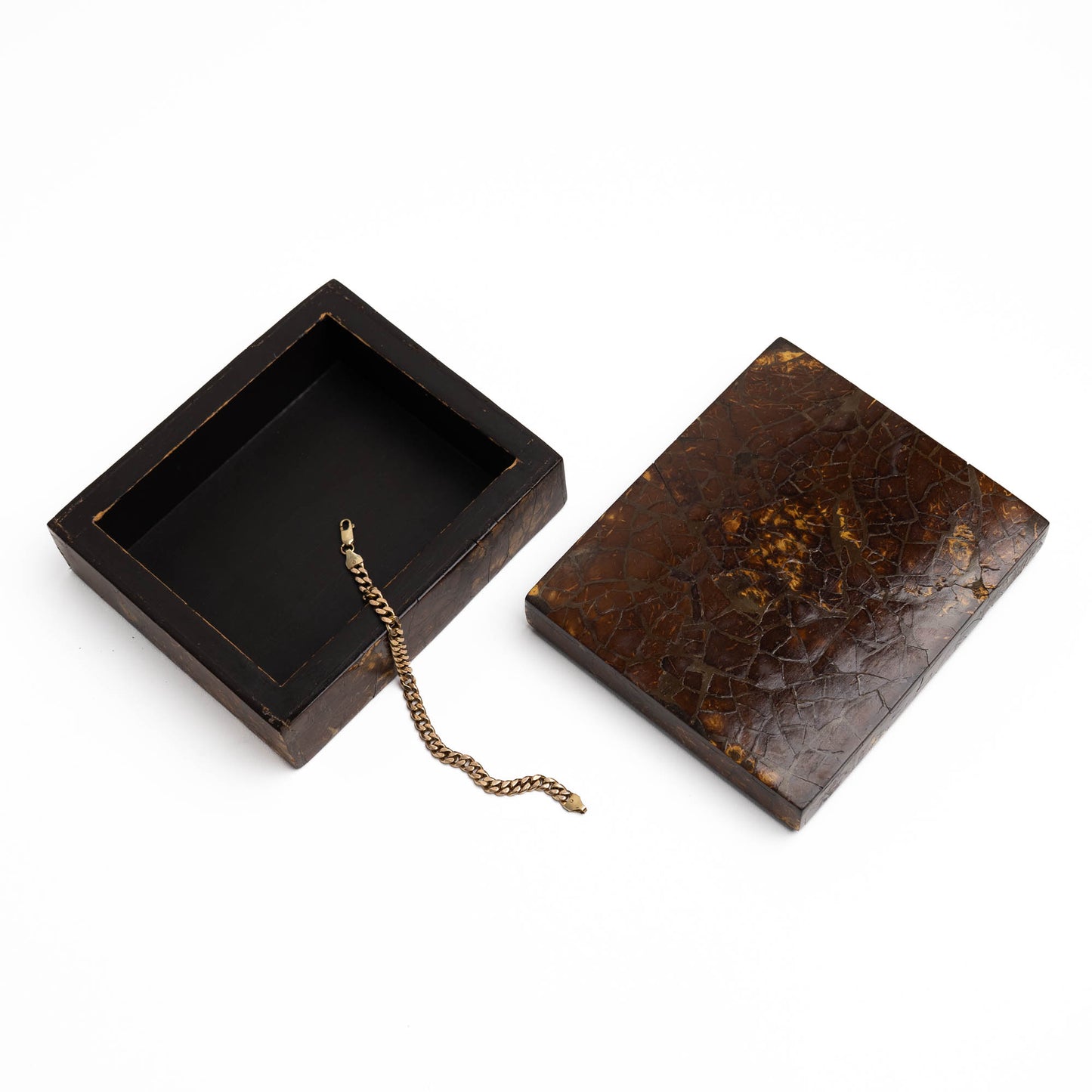A vintage dark brown wooden jewelry box shown open with its lid placed beside it on a white background. The interior is black, and a small gold bracelet rests inside the box.