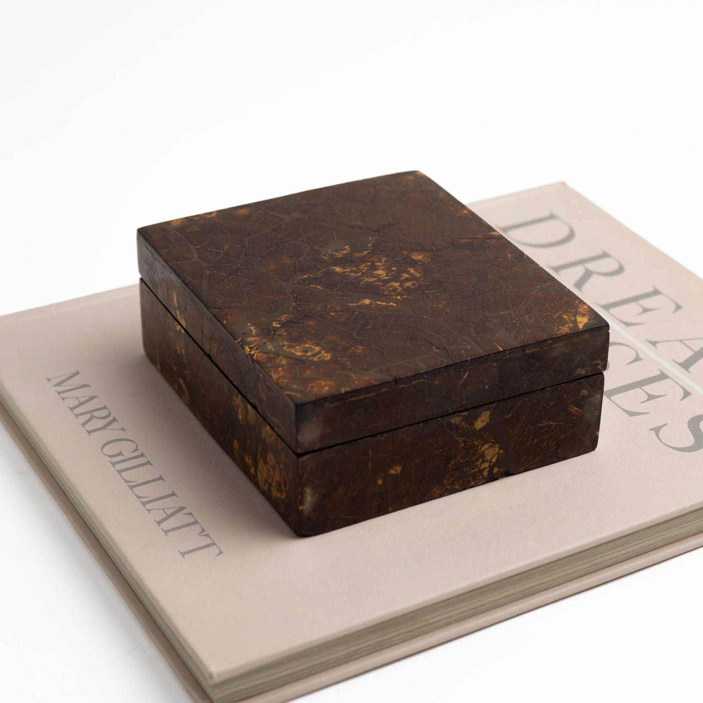 Tessellated coconut shell jewelry box styled as decor on a vintage coffee table book