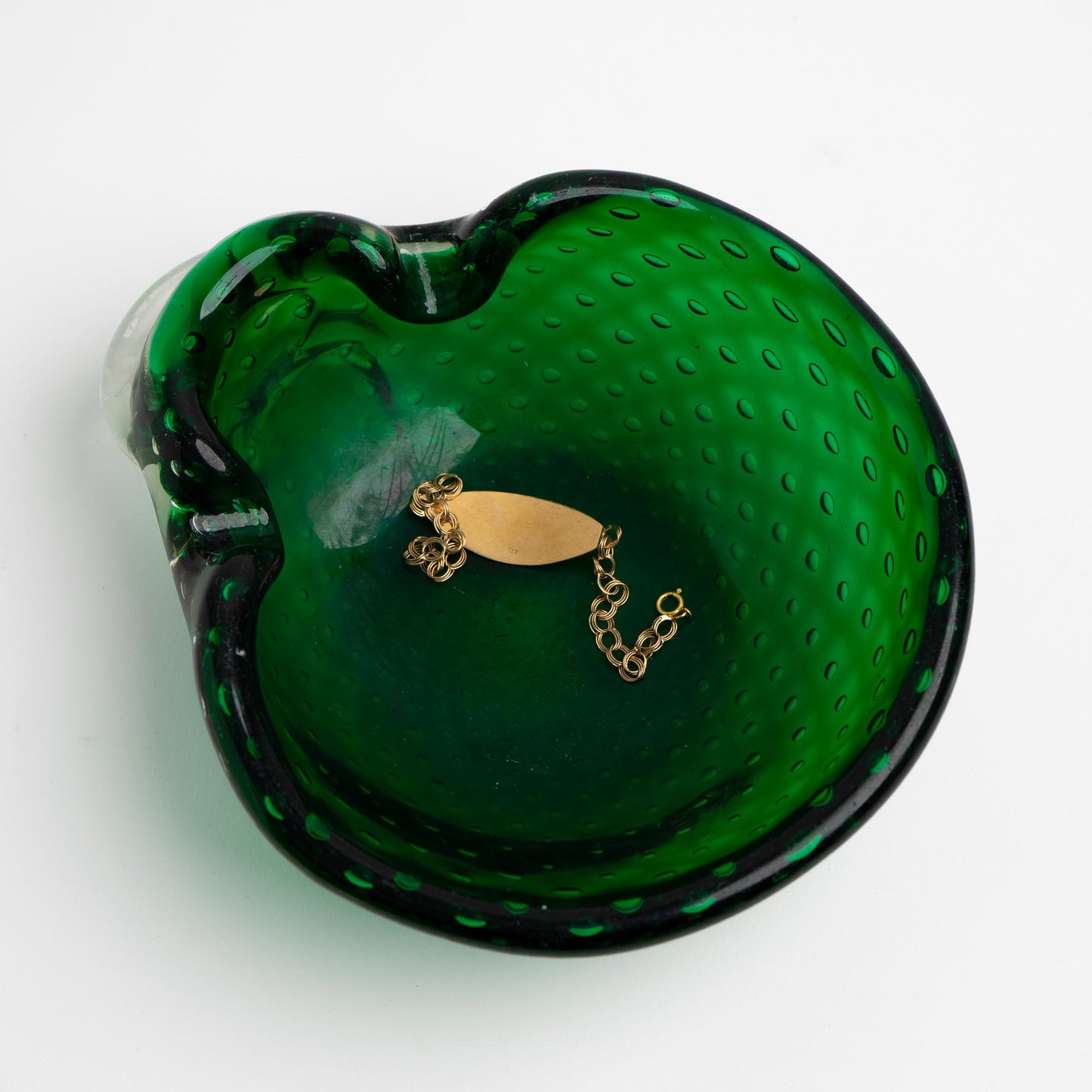Vintage emerald green Murano glass bullicante catchall dish with controlled bubble pattern, shown being used as a jewelry holder