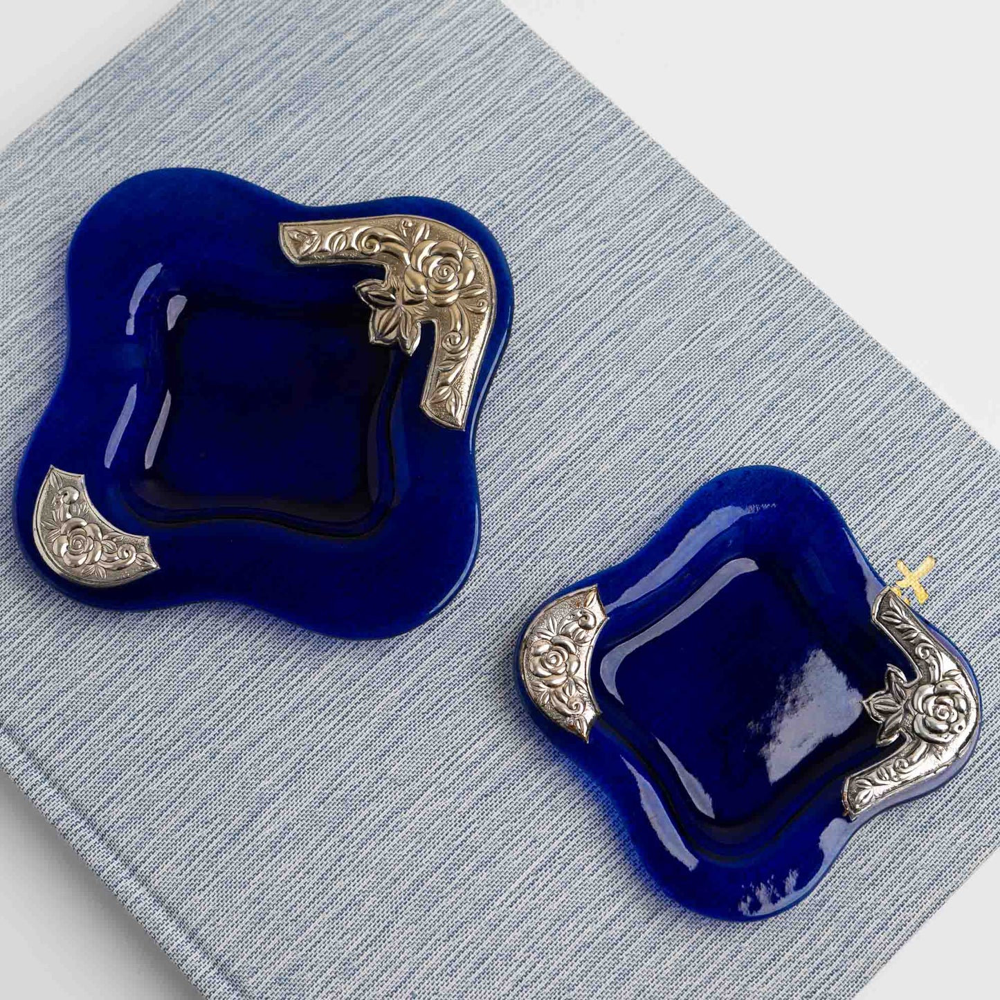 Set of two vintage cobalt blue square glass catchalls with silver-plated floral rose overlay design, styled on a vintage book