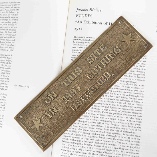 vintage brass rectangle plaque reading "On This Site in 1897 Nothing Happened"
