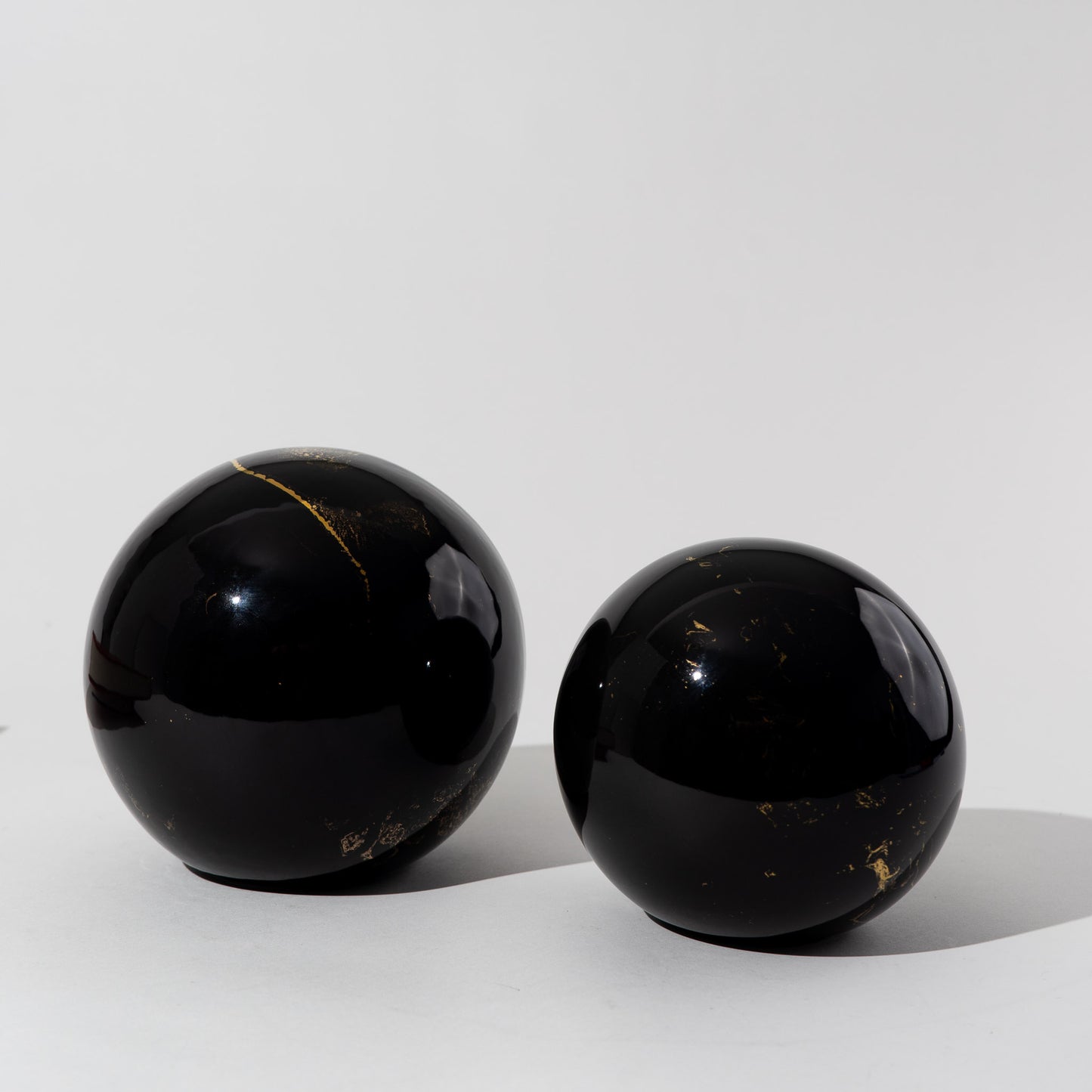 Pair of vintage black ceramic spheres with gold marbling, one large and one small, in the style of Sascha Brastoff
