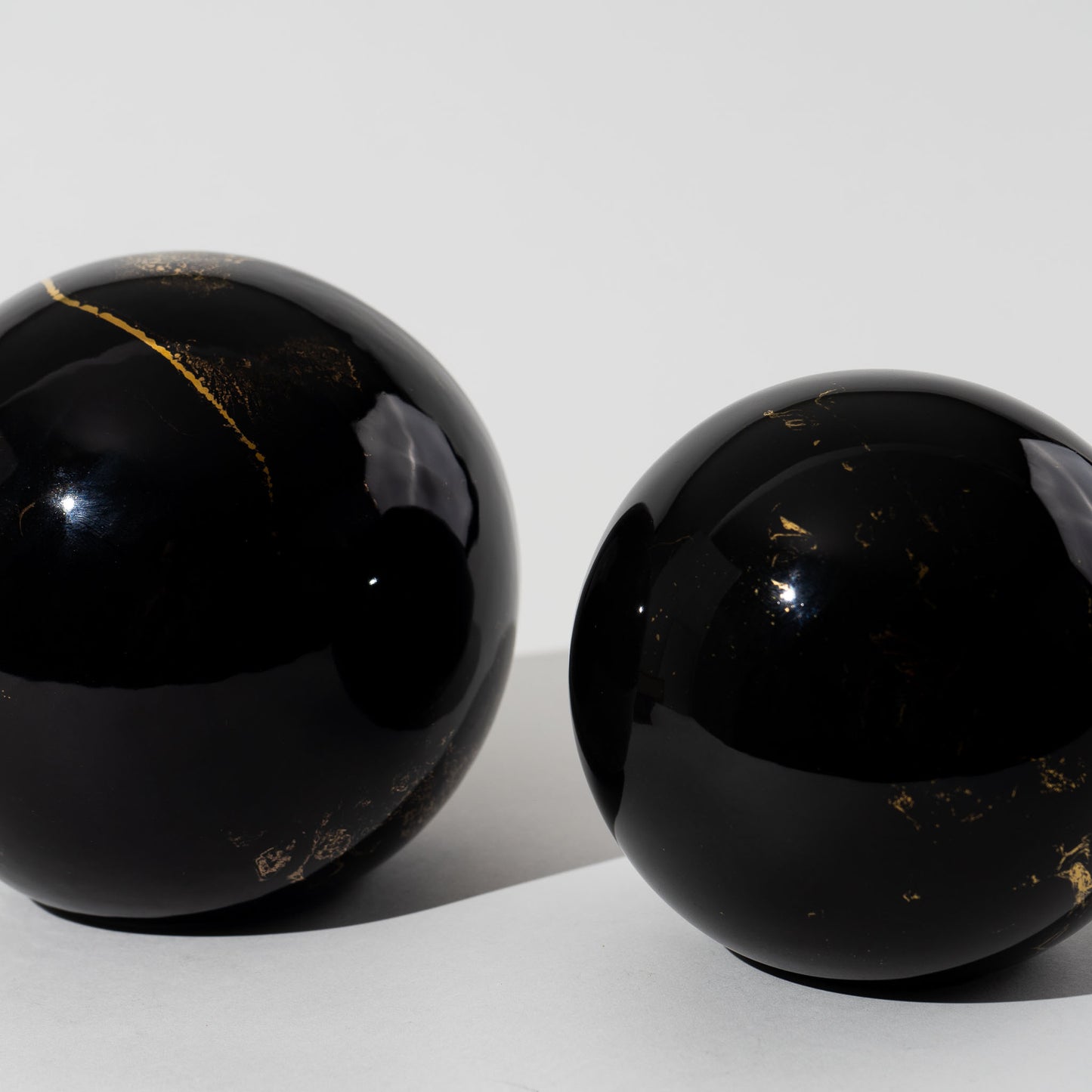 Pair of vintage black ceramic spheres with gold marbling, one large and one small, in the style of Sascha Brastoff