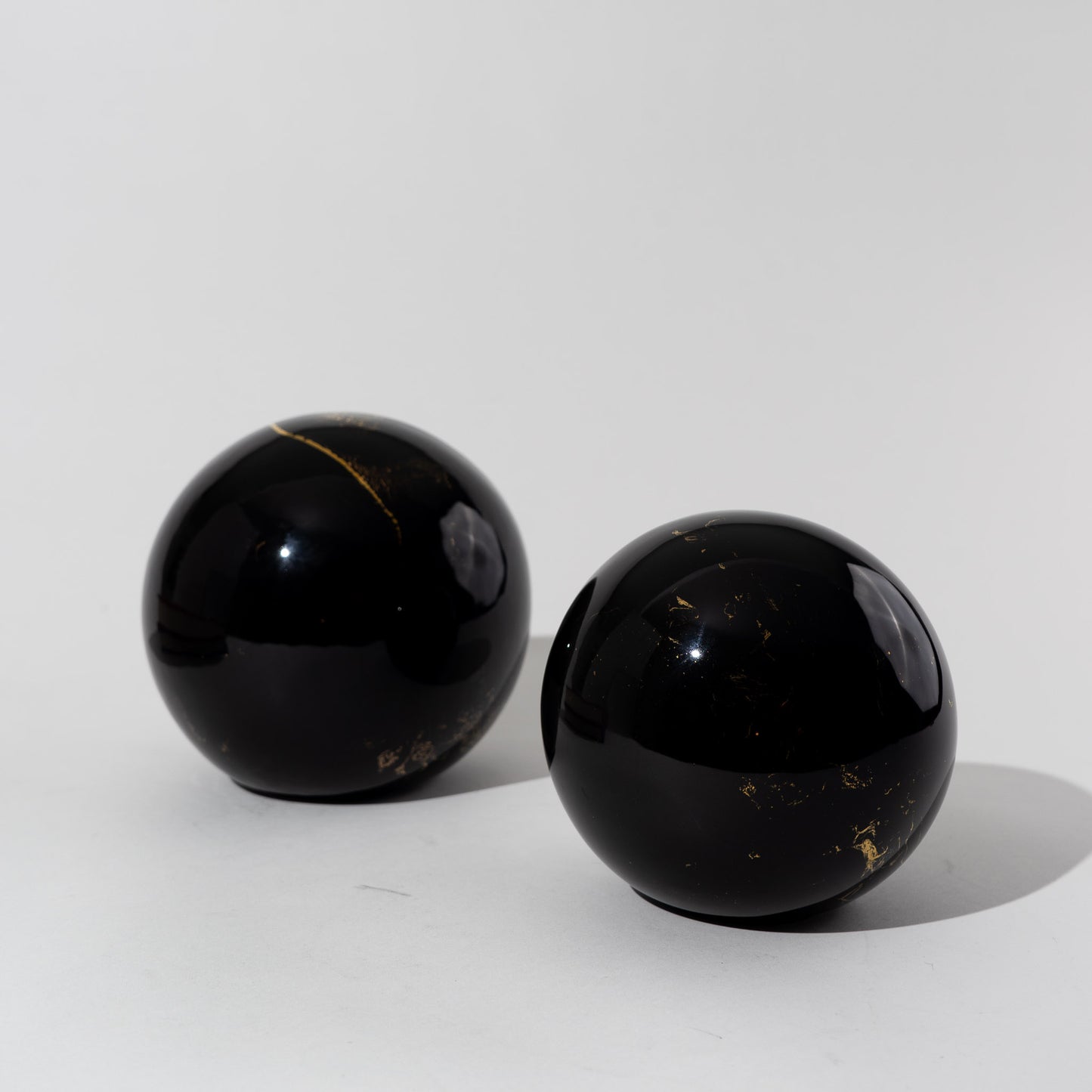 Pair of vintage black ceramic spheres with gold marbling, one large and one small, in the style of Sascha Brastoff