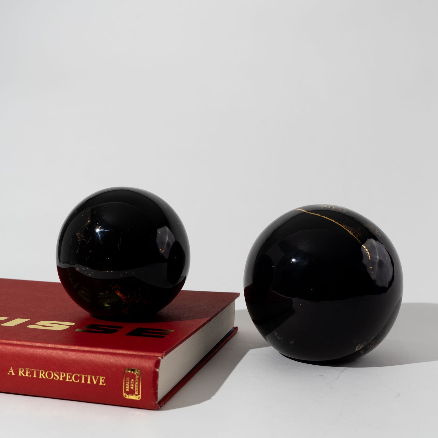 Pair of vintage black ceramic spheres with gold marbling, one large and one small, in the style of Sascha Brastoff