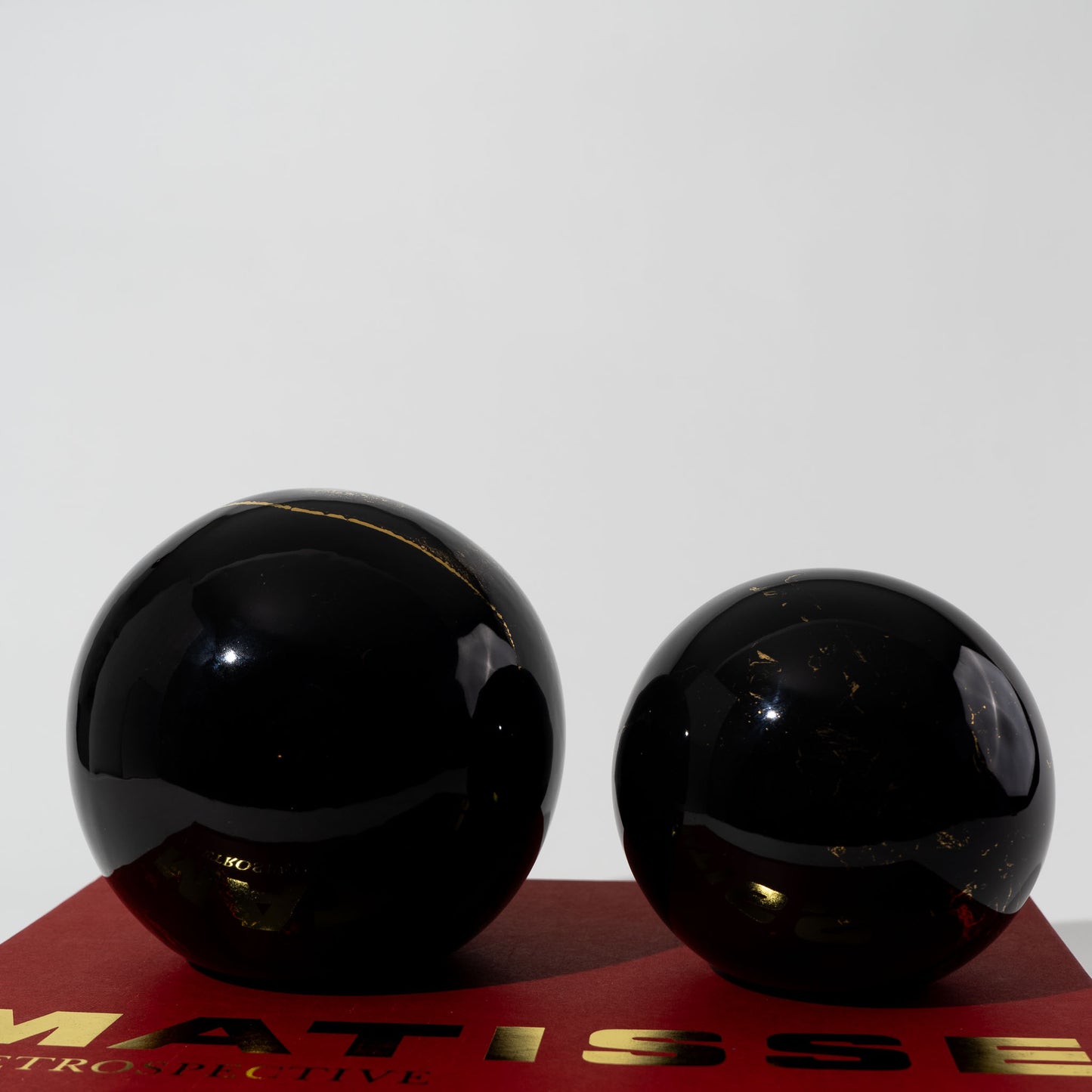 Pair of vintage black ceramic spheres with gold marbling, one large and one small, in the style of Sascha Brastoff