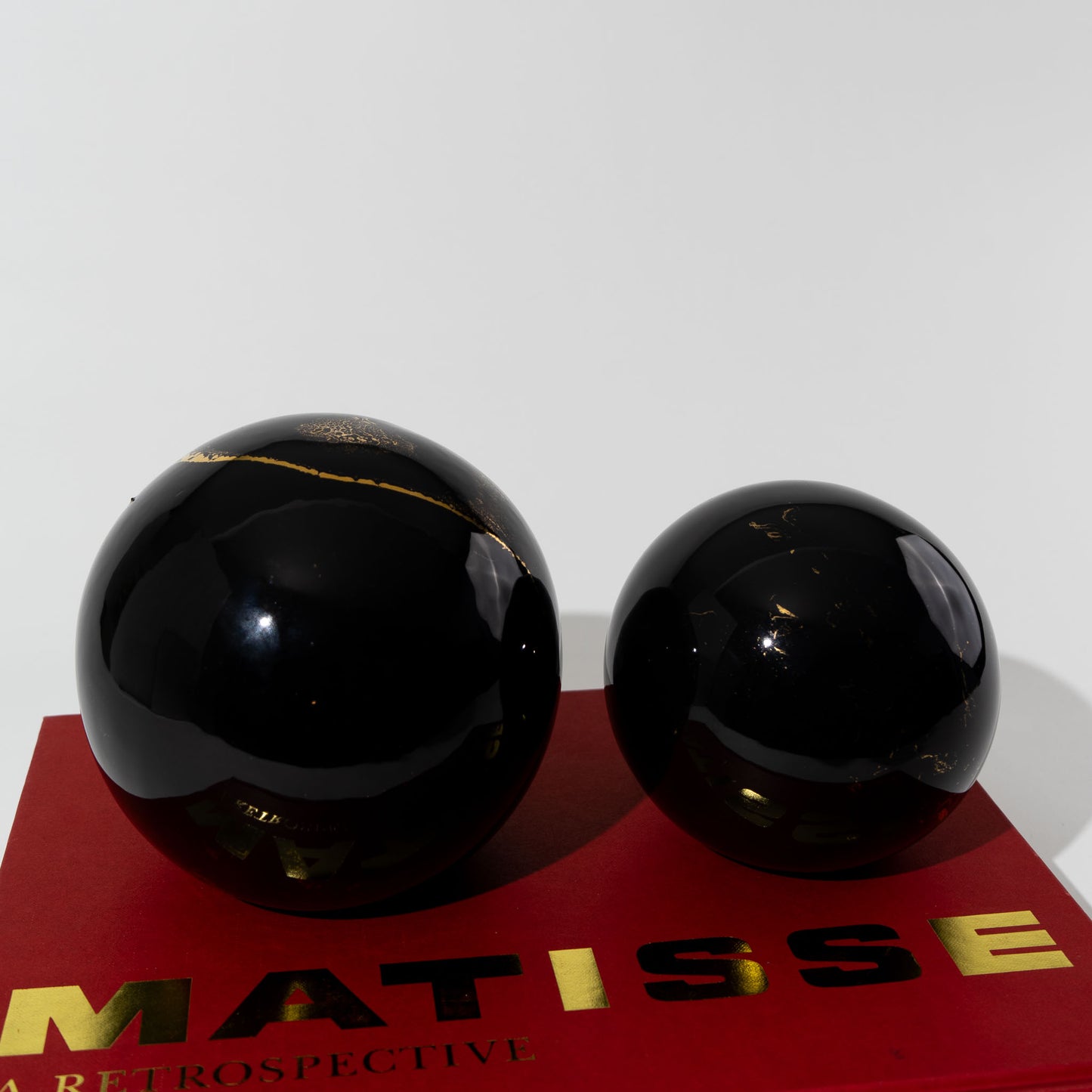 Pair of vintage black ceramic spheres with gold marbling, one large and one small, in the style of Sascha Brastoff