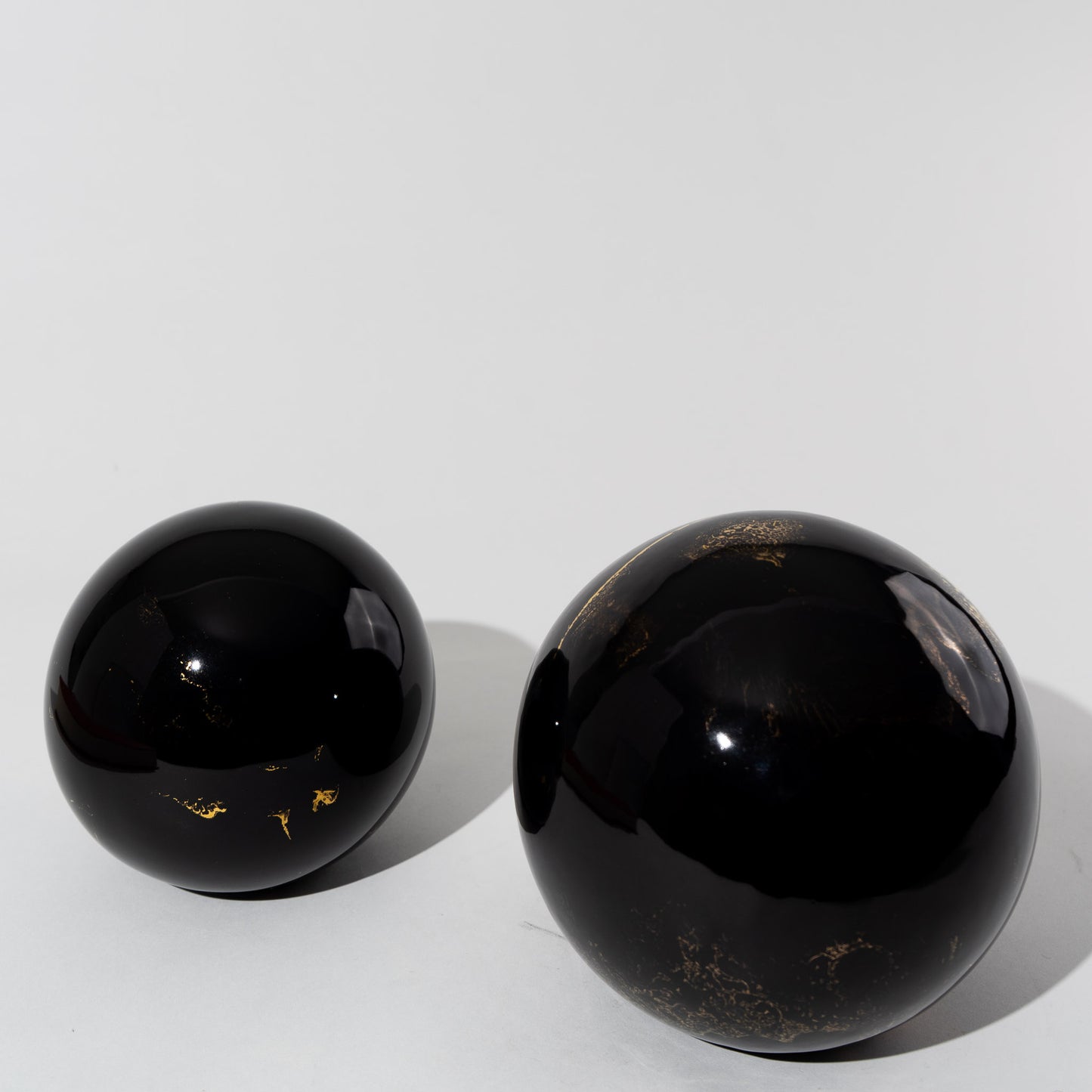 Pair of vintage black ceramic spheres with gold marbling, one large and one small, in the style of Sascha Brastoff