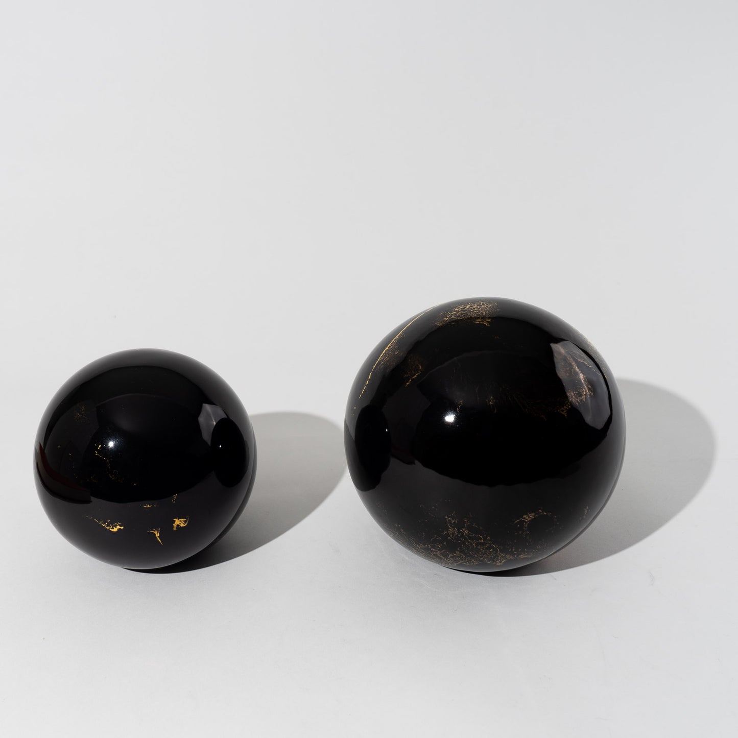 Pair of vintage black ceramic spheres with gold marbling, one large and one small, in the style of Sascha Brastoff
