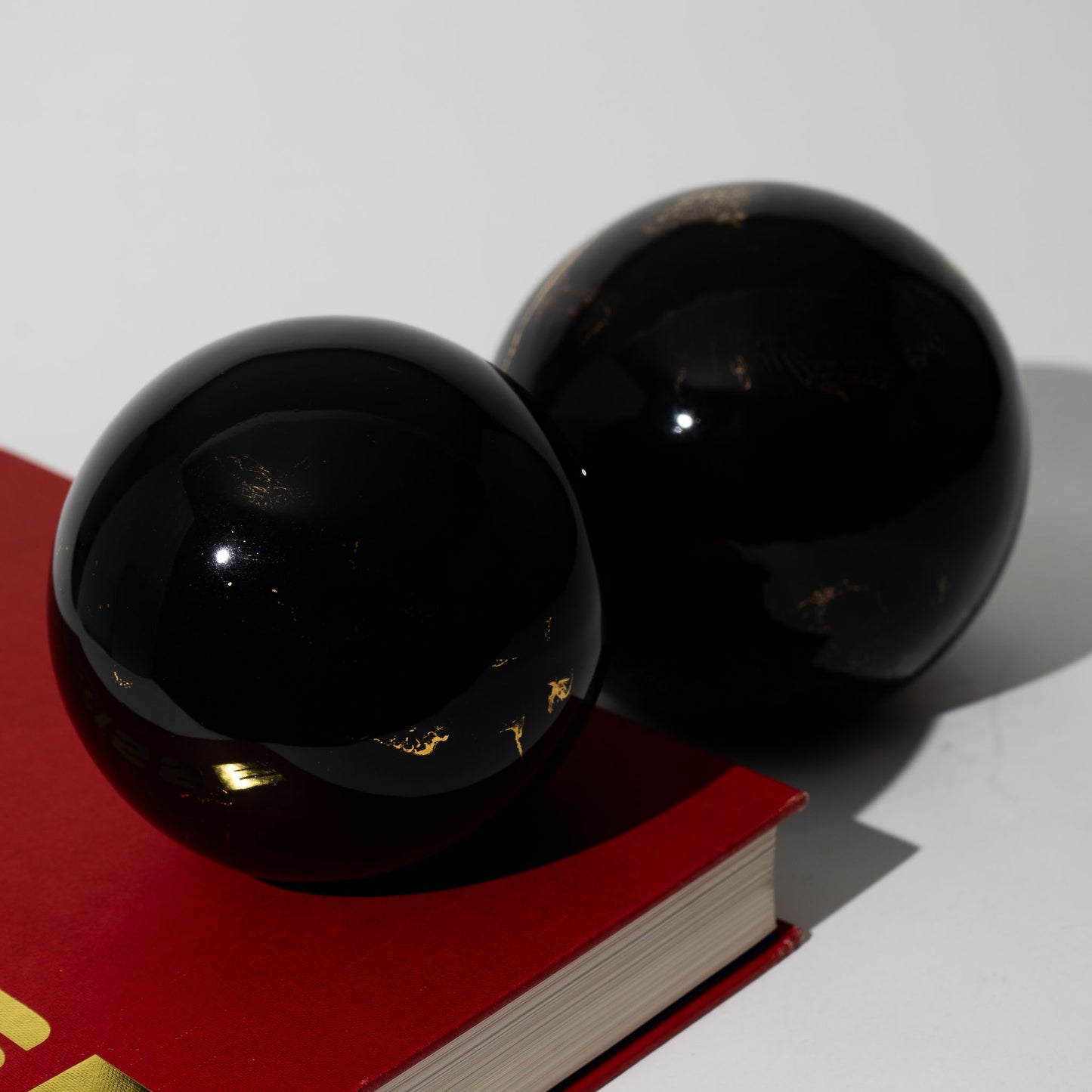 Pair of vintage black ceramic spheres with gold marbling, one large and one small, in the style of Sascha Brastoff