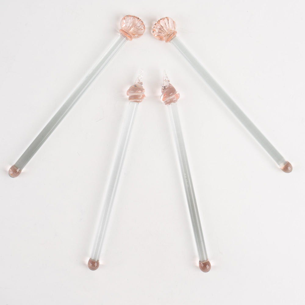 
                  
                    Set of four vintage glass drink swizzle sticks with seashell designs in light pink and clear glass, designed by Georges Briard.
                  
                
