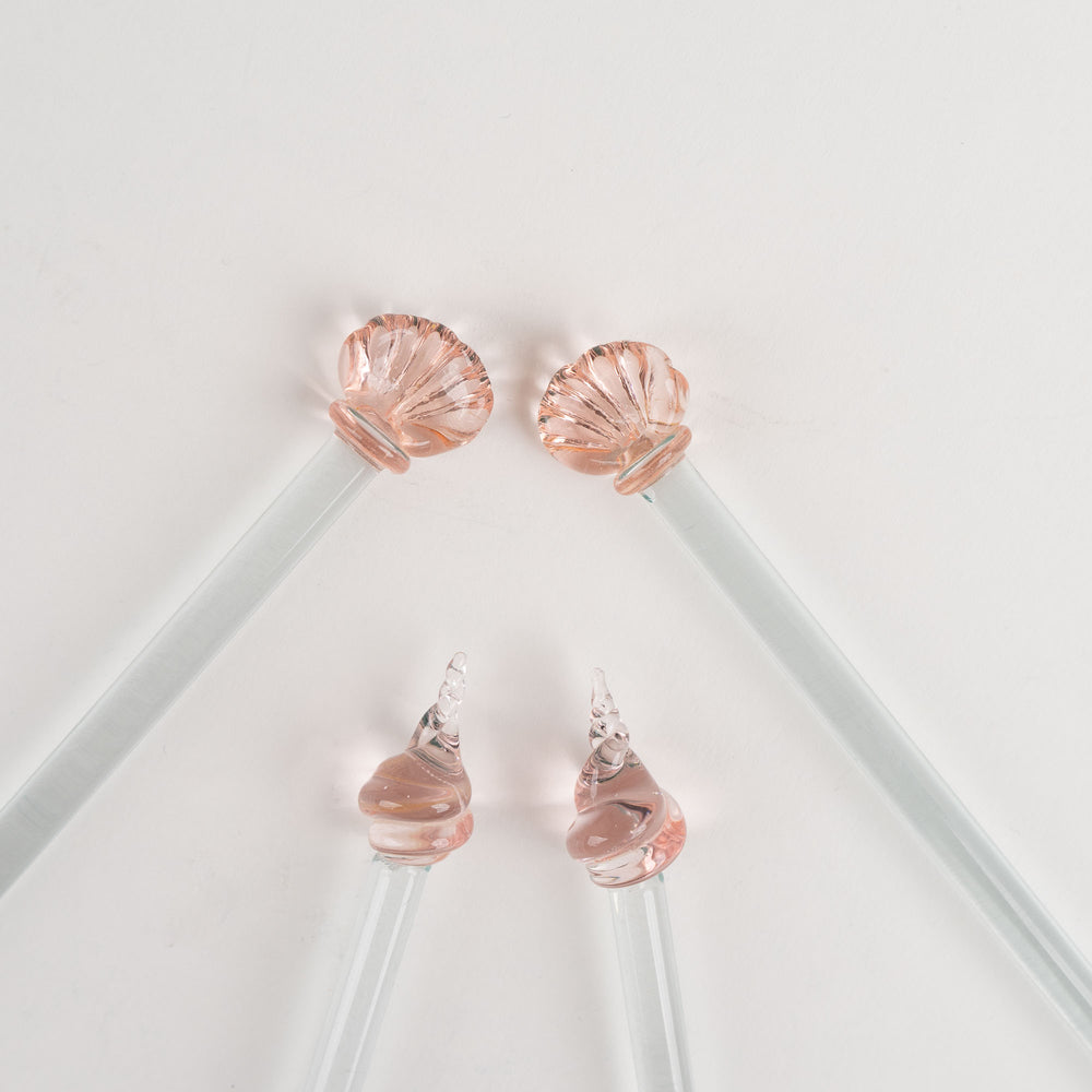 
                  
                    Set of four vintage glass drink swizzle sticks with seashell designs in light pink and clear glass, designed by Georges Briard.
                  
                