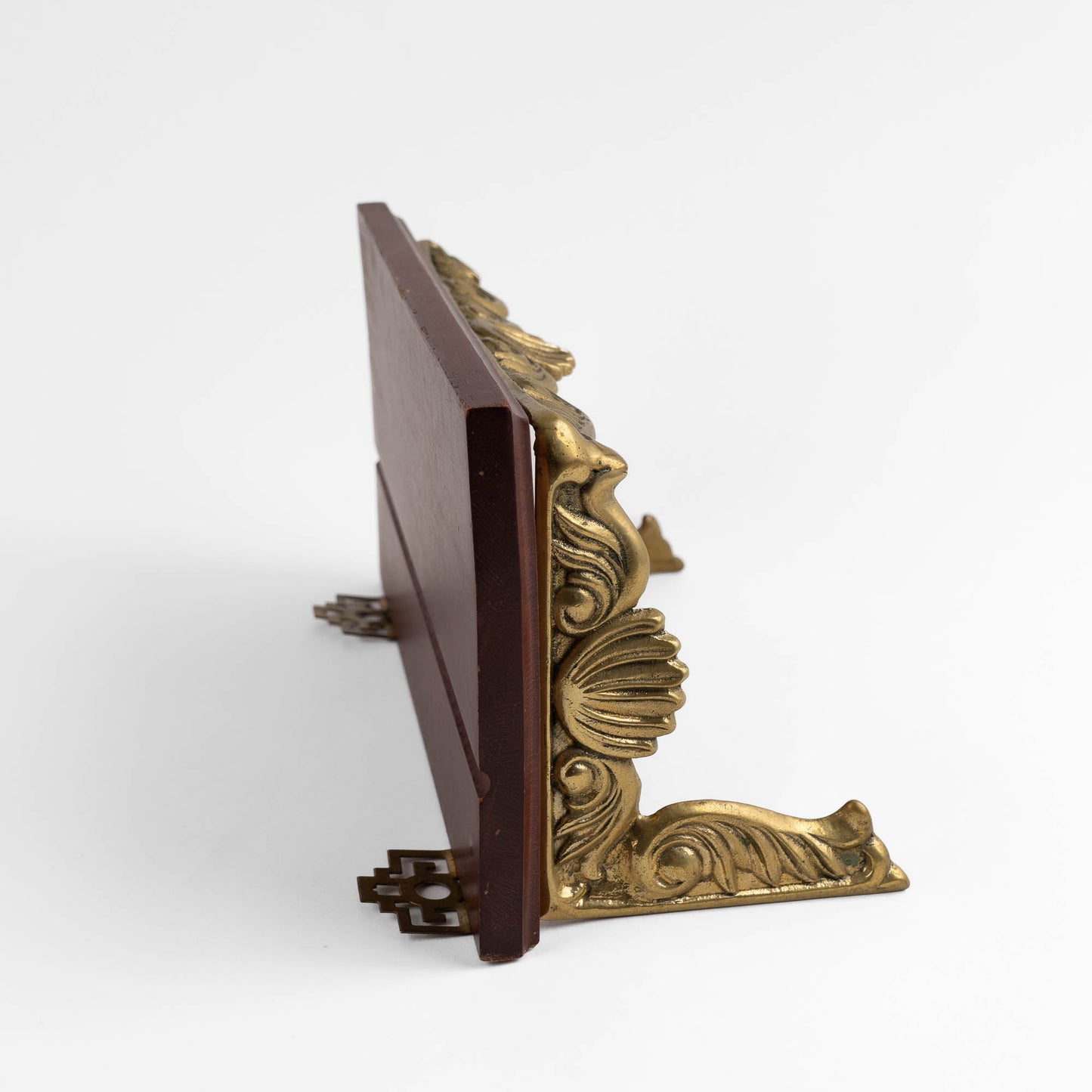 Vintage mid-century modern wall shelf with cherry wood surface, brass supports, and raised edge for displaying art
