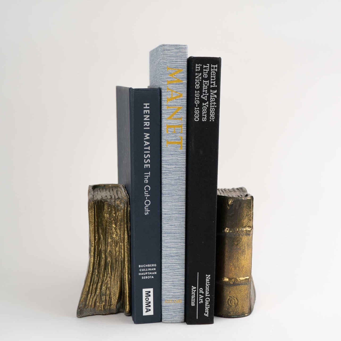 Pair of vintage brass bookends shaped like books, shown holding books on shelf