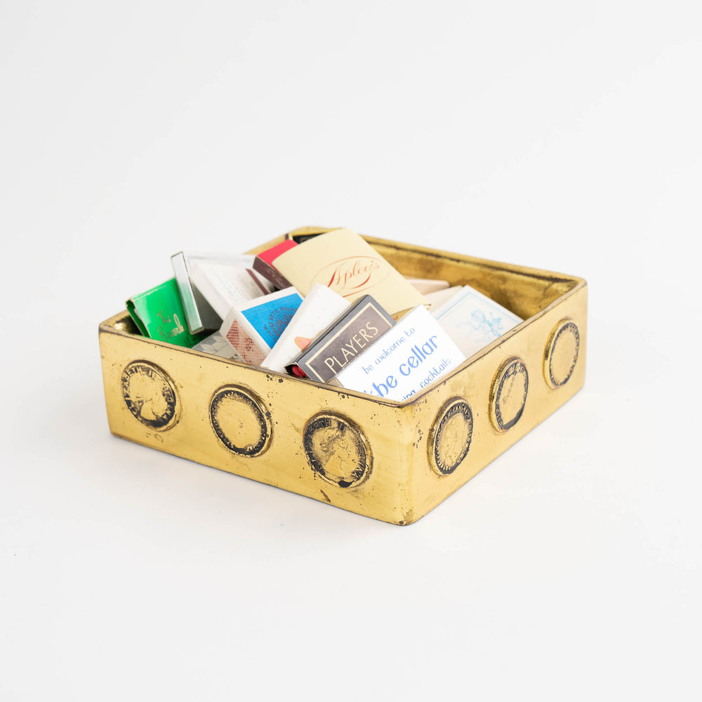 
                  
                    Vintage square brass ashtray featuring decorative historic Napoleon and Elizabeth coins, repurposed as jewelry catchall
                  
                