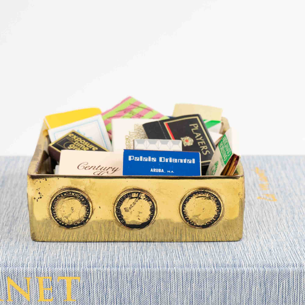 
                  
                    Vintage square brass ashtray featuring decorative historic Napoleon and Elizabeth coins, repurposed as jewelry catchall
                  
                