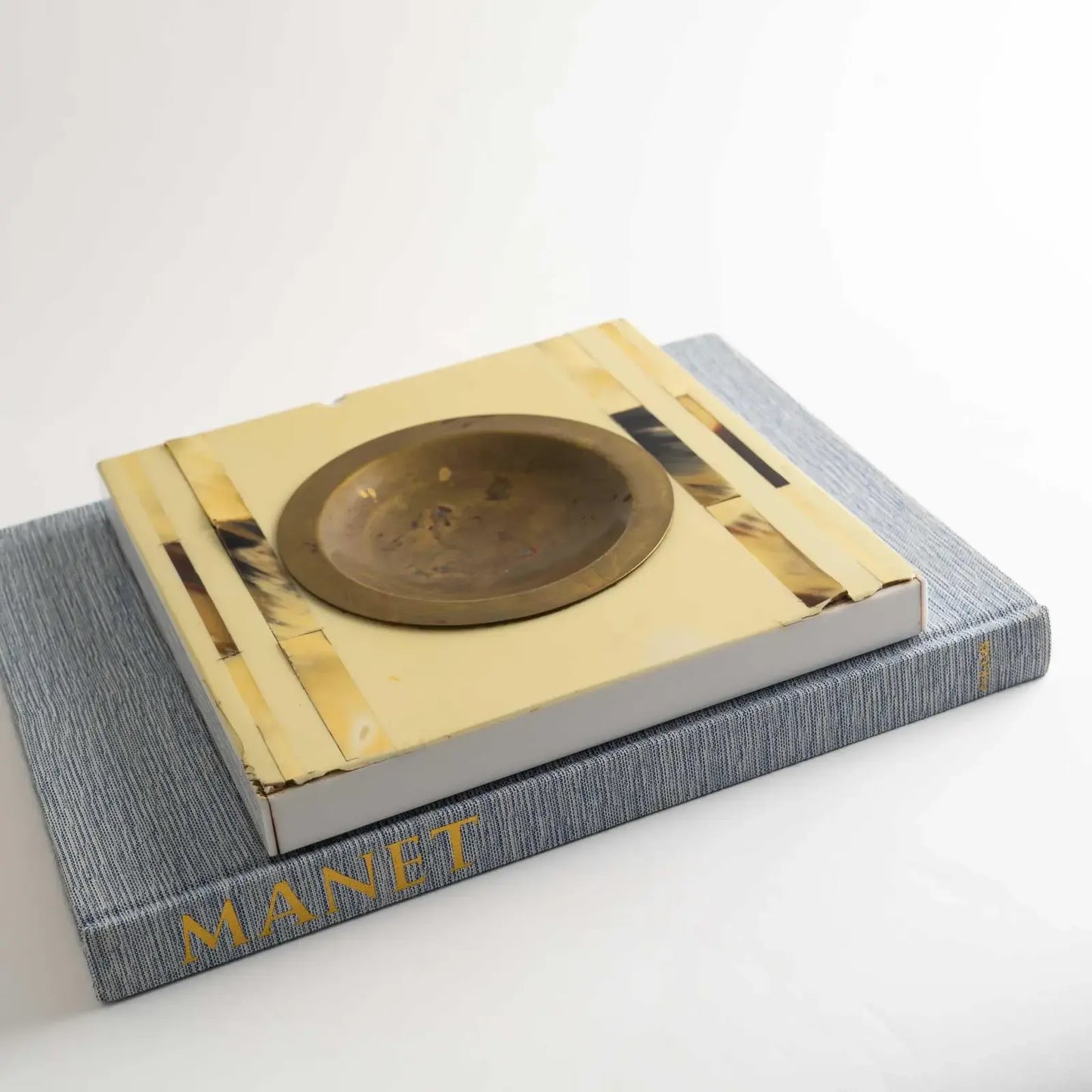 Vintage square horn inlay catchall with round brass ashtray center, styled on a vintage coffee table book