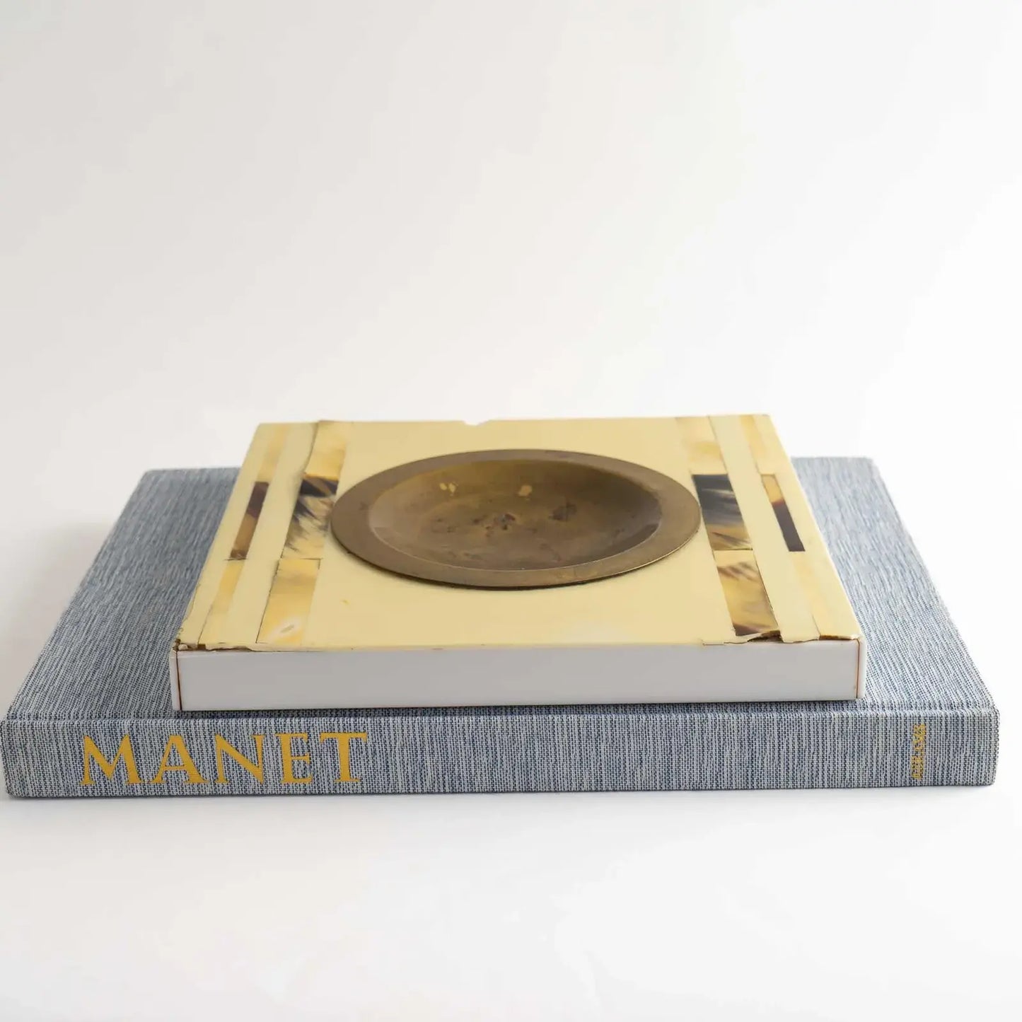 Vintage square horn inlay catchall with round brass ashtray center styled on top of a coffee table book
